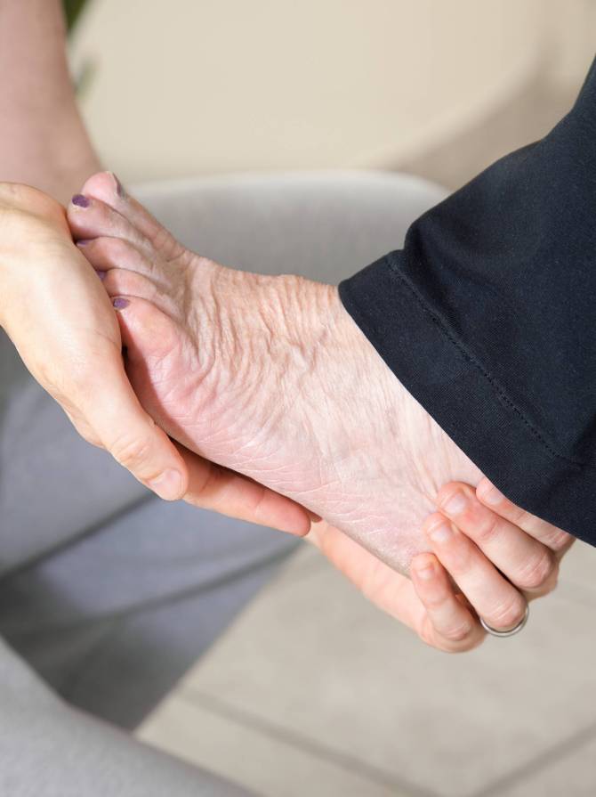 close-up-daughter-holding-legs-senior-mother